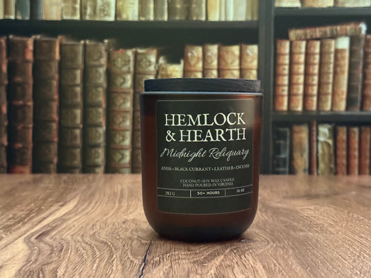 Candle labeled 'Hemlock & Hearth' on a wooden surface with bookshelf in the background