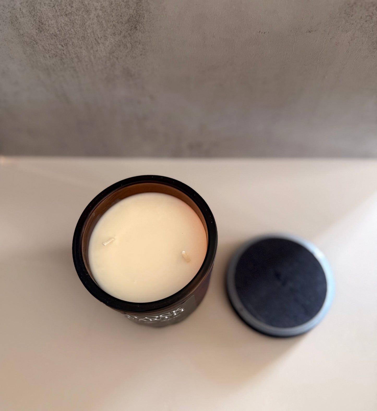 Candle in a glass jar with a wooden lid on a light surface.